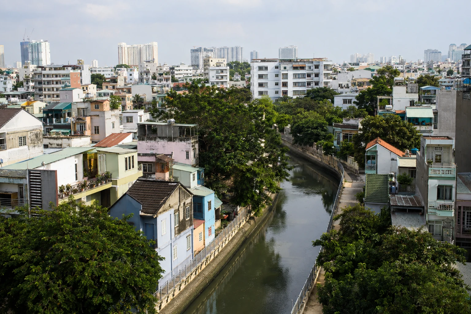 Dichtes Stadtquartier mit Wasserlauf, Wohnhäusern und tropischen Bäumen in Binh Thanh